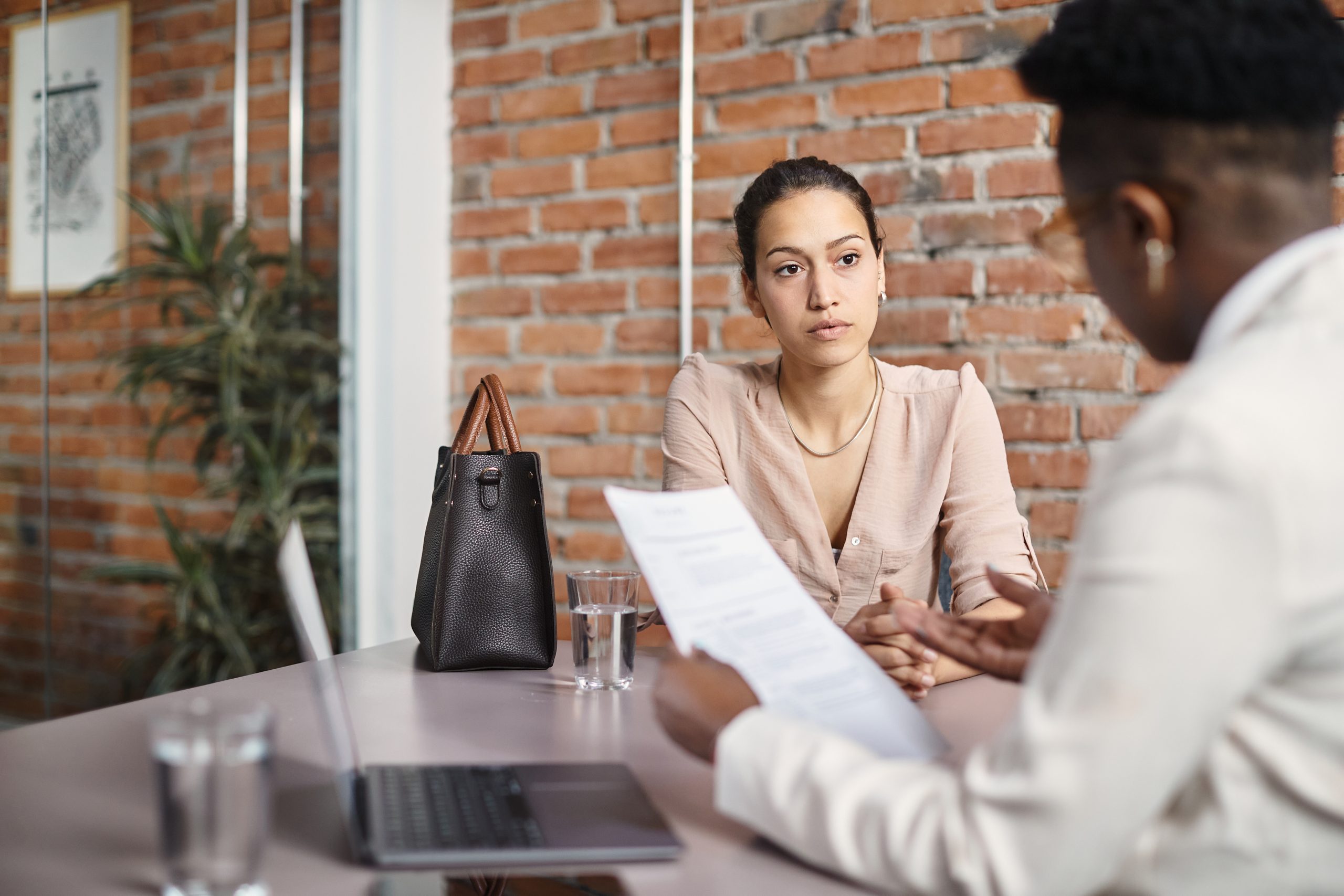 Young woman talking to member of human resource team while applying for job in the office.